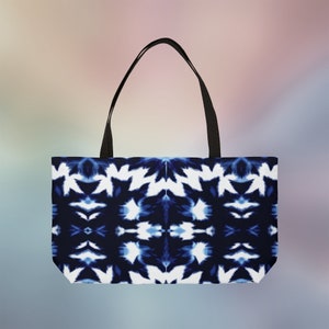 May include: A blue and white tote bag with a tie-dye pattern. The bag has black handles.