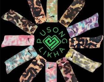 May include: A collection of colorful tie-dye socks arranged in a circular pattern against a black background. Each sock features a Nike logo and unique patterns in shades of pink, blue, green, and brown. The text "PUSONG LIKHA" is in the center.