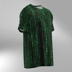 May include: Black t-shirt with a green digital rain pattern. The design features vertical lines of green characters, creating a code-like appearance. The short-sleeved shirt has a crew neck and a relaxed fit.