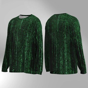 May include: Long-sleeved shirt featuring a black and green digital rain design. The pattern, reminiscent of computer code, covers the front and back of the shirt. It has a crew neck and long sleeves. The design is a series of vertical lines of green characters.