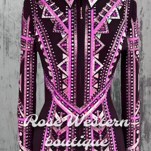 Op de afbeelding: Een zwart showjack met roze en witte geometrische ontwerpen en strass. Het jack heeft een ritssluiting en lange mouwen. De tekst "Rose Western Boutique" is zichtbaar op de voorkant van het jack.