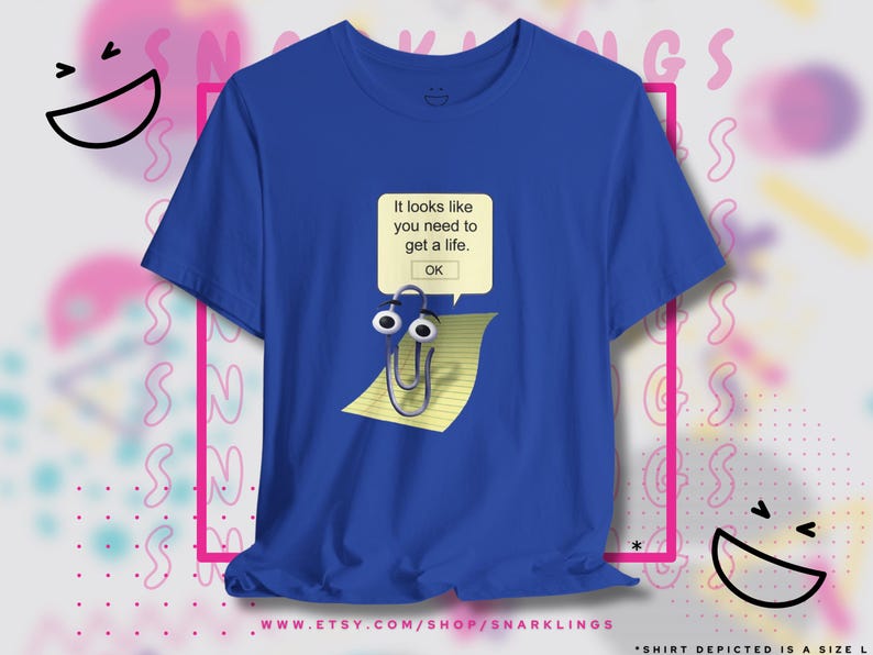 May include: A royal blue t-shirt with a white paperclip with googly eyes on a yellow piece of lined paper. The paperclip is walking across the paper. The text on the shirt reads "It looks like you need to get a life. OK."