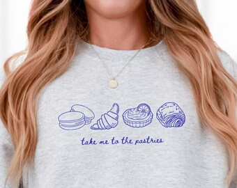 May include: A gray sweatshirt with a blue graphic of pastries and the text "Take me to the pastries".