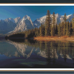 May include: A scenic landscape photograph featuring a mountain range reflected in a still lake. The mountains are snow-capped and the lake is surrounded by a forest of evergreen trees.