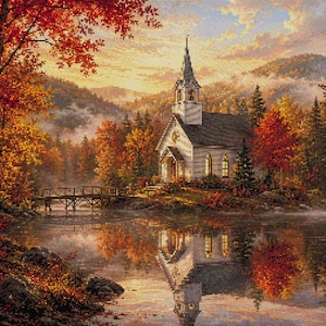 Puede incluir: Un patrón de punto de cruz que representa una iglesia blanca con campanario situada a orillas de un lago, rodeada de árboles otoñales con follaje rojo, naranja y amarillo. Un puente de madera cruza el agua y la escena se refleja en el lago.