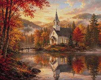 May include: A cross-stitch pattern depicting a white church with a steeple situated on a lake shore surrounded by autumn trees with red, orange, and yellow foliage. A wooden bridge spans the water, and the entire scene reflects in the lake.