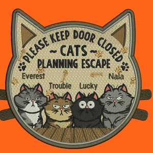 May include: A brown cat-shaped door sign with the text "Please keep door closed - Cats planning escape" and four paw prints. The sign features four cats with names: Everest, Trouble, Lucky, and Nala.