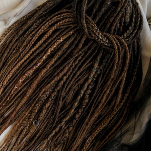 May include: A set of brown and blonde synthetic dreadlocks with copper and blue accents. The dreadlocks are tied together at the top.