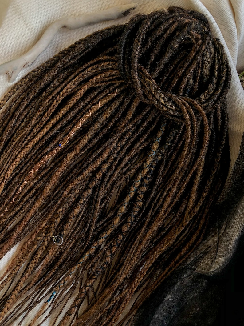 May include: A set of brown and blonde synthetic dreadlocks with copper and blue accents. The dreadlocks are tied together at the top.