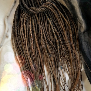 May include: A set of brown synthetic dreadlocks with a few strands of blue and gold. The dreadlocks are tied together at the top.