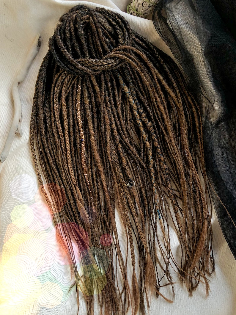 May include: A set of brown synthetic dreadlocks with a few strands of blue and gold. The dreadlocks are tied together at the top.