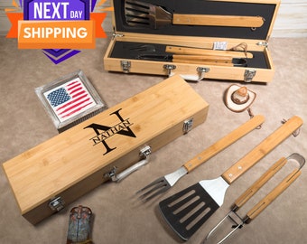 Puede incluir: Un juego de herramientas de barbacoa de bambú con una caja grabada personalizada. La caja está grabada con el nombre "Nathan" y tiene un asa. El juego incluye una espátula, unas pinzas y un tenedor. Las herramientas tienen mangos de madera y cabezales de acero inoxidable.