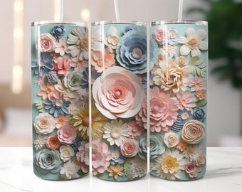 May include: Three stainless steel tumblers with a light blue background and a pattern of colourful paper flowers. The flowers are in shades of pink, blue, yellow, and white.