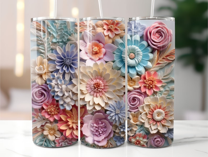May include: Three stainless steel tumblers featuring a floral design. The tumblers are adorned with a range of pastel-coloured flowers, including roses, daisies, and lilies. The flowers are arranged in a realistic, three-dimensional style, giving the tumblers a unique and eye-catching appearance.
