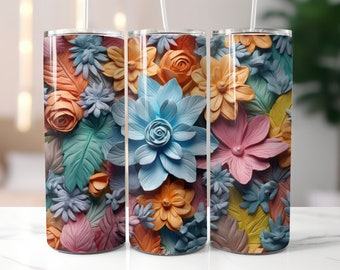 May include: Three stainless steel tumblers with a colorful floral pattern. The tumblers feature a variety of flowers in shades of blue, pink, yellow, and orange. The flowers are arranged in a random pattern and appear to be made of paper or fabric.