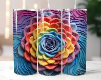 May include: A stainless steel tumbler featuring a colourful rainbow flower design. The flower is made up of petals in shades of red, orange, yellow, green, blue, and purple. The background is a textured blue and purple design.