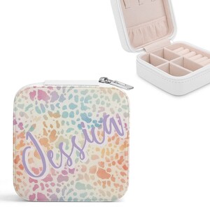 May include: White square jewelry box with a zipper closure and a colorful spotted pattern. The box is open, revealing compartments for rings and other jewelry. The name "Jessica" is written in a cursive font on the front.