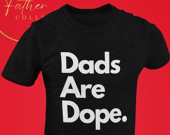 Peut inclure: T-shirt noir avec un texte blanc qui dit "Dads Are Dope."