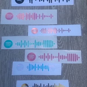 May include: Seven different Spotify barcode stickers in various colours, including black, pink, rose gold, teal, light pink, light blue, and gold.