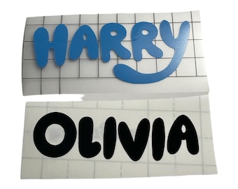 May include: Two sheets of white vinyl with names written in bubble letters. The top sheet has the name "HARRY" in blue. The bottom sheet has the name "OLIVIA" in black.