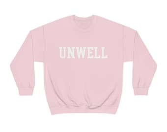 Puede incluir: Una sudadera rosa con la palabra "UNWELL" impresa en blanco en la parte delantera.