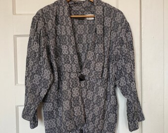 May include: A black and white patterned jacket with a V-neck and long sleeves. The jacket has a button closure and a relaxed fit.