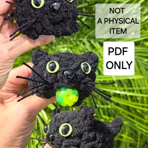 May include: Three black plush cat toys with green googly eyes and black yarn whiskers. Each cat has a green plastic ball in its mouth. The text "NOT A PHYSICAL ITEM PDF ONLY" is visible in the image.