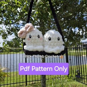 May include: A crochet pattern for a cute ghost-shaped bag with a pink bow. The bag is hanging from a black strap and has the text "Thick Thumb Crochet" and "Pdf Pattern Only" on it.