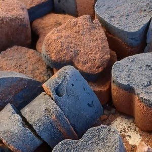 May include: A pile of heart-shaped concrete blocks in shades of brown and gray. The blocks are rough and textured, with a rustic appearance.