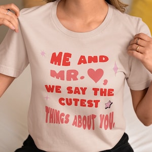 May include: A light pink t-shirt with a graphic print that says "Me and Mr. ♥ We say the cutest things about you."