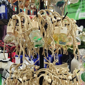 May include: A display of small, clear glass bottles with cork tops and twine hangers. The bottles are filled with colorful glitter and are arranged in a tiered display.