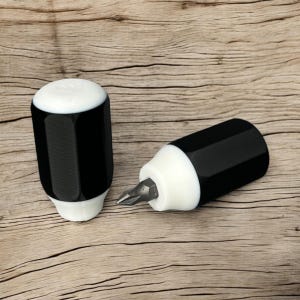 May include: Two black and white screwdriver tools with a hexagonal barrel and a white tip. The tools are on a wooden surface.