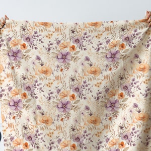 May include: A beige fabric with a floral pattern featuring purple and orange flowers. The fabric has a subtle texture and a vintage aesthetic.