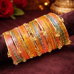 Könnte beinhalten: Eine Sammlung bunter Armreifen mit goldenen Akzenten. Die Armreifen sind auf einer dunkelvioletten Oberfläche angeordnet. Die Armreifen sind eine Mischung aus Orange, Gelb, Grün und Blau. Das Bild enthält den Text "ShifanTrendHub".