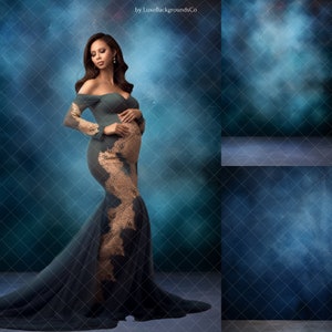 May include: A pregnant person wearing a teal and gold mermaid-style gown with lace detailing, standing against a blue and green textured backdrop. The background has a soft, hazy effect.