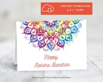 May include: A white greeting card with a colorful mandala design in shades of red, orange, yellow, green, blue, and purple. The words "Happy Raksha Bandhan" are written in red script. The card is 5 x 7 inches.