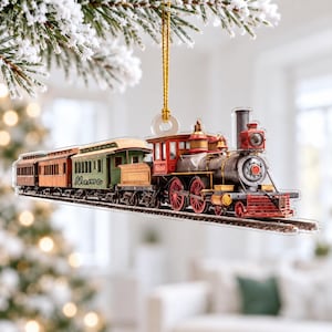 May include: A flat, hanging Christmas tree ornament shaped like a steam locomotive train with attached passenger cars. The train features red, green, and metallic gray details, with the word Name printed in black script on the green car.