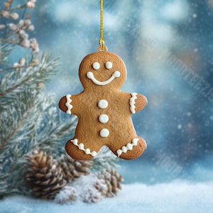 K&ouml;nnte beinhalten: Ein Lebkuchenmann-Weihnachtsschmuck mit wei&szlig;en Zuckergussdetails und einem l&auml;chelnden Gesicht. Der Schmuck h&auml;ngt an einem goldenen Faden vor einem verschwommenen, schneebedeckten Hintergrund mit Tannenzweigen und Zapfen.