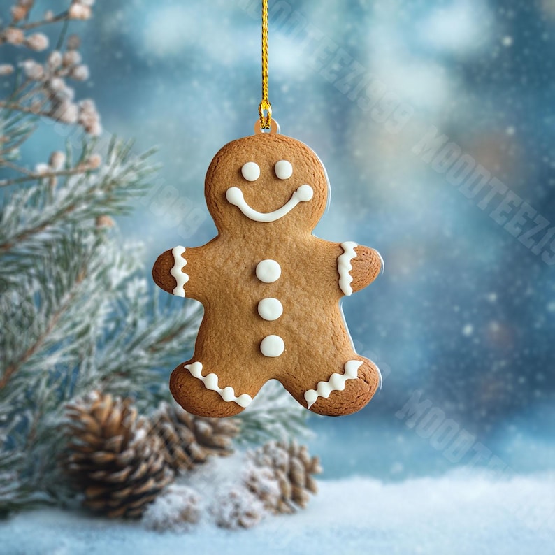 K&ouml;nnte beinhalten: Ein Lebkuchenmann-Weihnachtsschmuck mit wei&szlig;en Zuckergussdetails und einem l&auml;chelnden Gesicht. Der Schmuck h&auml;ngt an einem goldenen Faden vor einem verschwommenen, schneebedeckten Hintergrund mit Tannenzweigen und Zapfen.