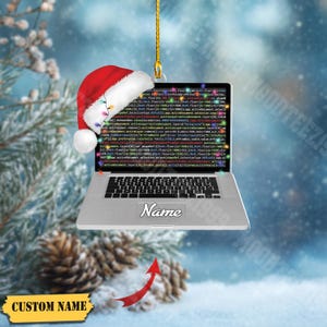 May include: A silver laptop Christmas ornament with a Santa hat, displaying code on the screen. The ornament has a gold string for hanging and includes the text "Name" and "CUSTOM NAME".