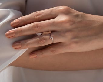 May include: A delicate gold ring with a lightning bolt design set with small diamonds.