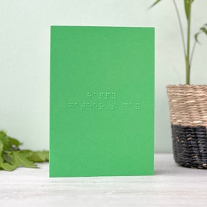 A vibrant green portrait card with happy father's day written in grade 1 UEB braille.