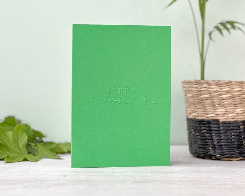 A vibrant green portrait card with happy father's day written in grade 1 UEB braille.