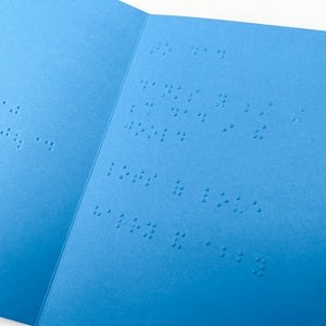 Image shows an open blue Father's Day card with text inside that reads to dad, thanks for being the best dad in the world, lots of love harry and abby, in lower case grade 2 UEB braille.