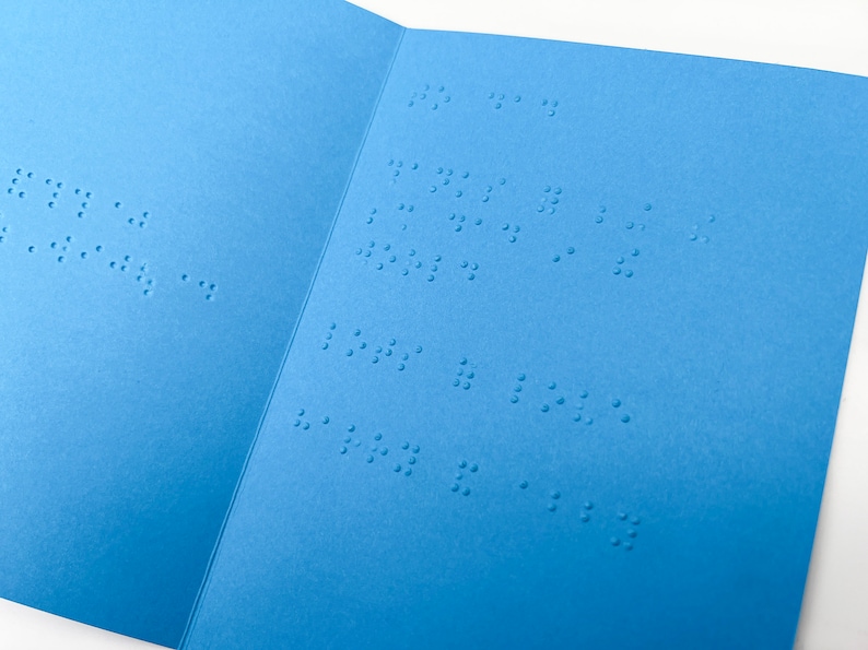 Image shows an open blue Father's Day card with text inside that reads to dad, thanks for being the best dad in the world, lots of love harry and abby, in lower case grade 2 UEB braille.