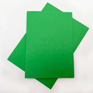 Image shows a green card with the words happy father's day written in grade 1 UEB braille. A matching green envelope is beneath the card.