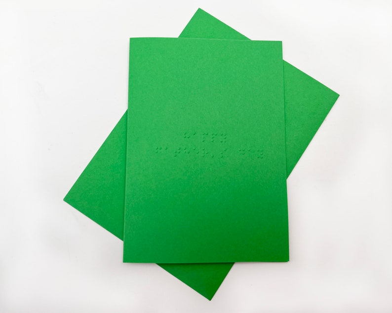 Image shows a green card with the words happy father's day written in grade 1 UEB braille. A matching green envelope is beneath the card.