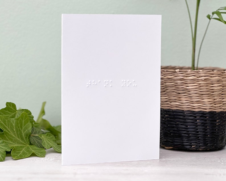 A white portrait greetings card with thank you written in braille.