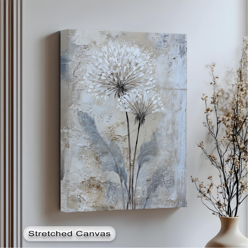 a stretched canvas artwork depicting two white flowers with long stems, hanging on a wall next to a vase with dried flowers.