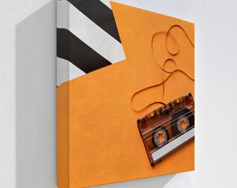 May include: A stretched canvas art piece featuring a retro cassette tape design. The artwork has an orange background with a black and white striped corner. The text "Stretched Canvas" is at the bottom.